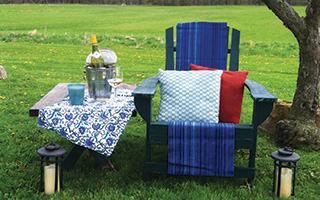 A comfortable seat with plump pillows makes this shady spot the perfect place to unwind on a warm evening. A few well-placed citronella candles help keep the bugs at bay.