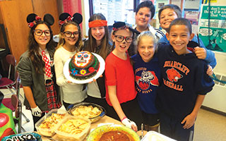 Briarcliff Middle School Spanish students pose with the Mexican food they made for El Dia de los Muertos.