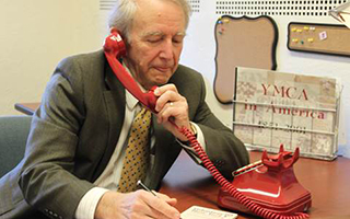Civic leader, Paul Schwarz, the son of Volunteer New York! Co-founder, Jane Schwarz, seen here recreating the first ever volunteer-to-nonprofit connection made 65 years ago at a borrowed desk at the YMCA of White Plains. Photo Credit: Volunteer New York!