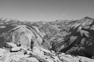 Two hikers pause to take in the seemingly unending  Yosemite Valley, California after a taxing journey to the summit of Half Dome.