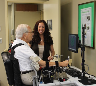 A stroke survivor utilizing wrist robot for functional wrist and hand motion with Avrielle Rykman Peltz, Chief Operating Officer of the Restorative Neurology Clinic.