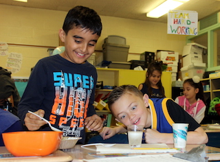 Claremont School fourth-graders Mohammad Waris and Nick Cerbone conduct a dancing raisins experiment during the school’s recent Enrichment Day.